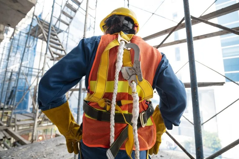 Trabalhador utilizando cinto de seguranca tipo paraquedista em obra