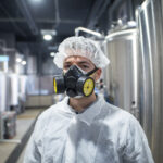 Trabalhador industrial utilizando respirador e uniforme de protecao