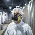 Trabalhador industrial utilizando respirador e uniforme de protecao