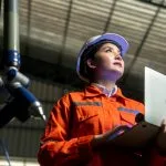 Engenheira com capacete utilizando notebook em industria 4.0