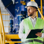 Trabalhador de colete anotando checklist em fabrica